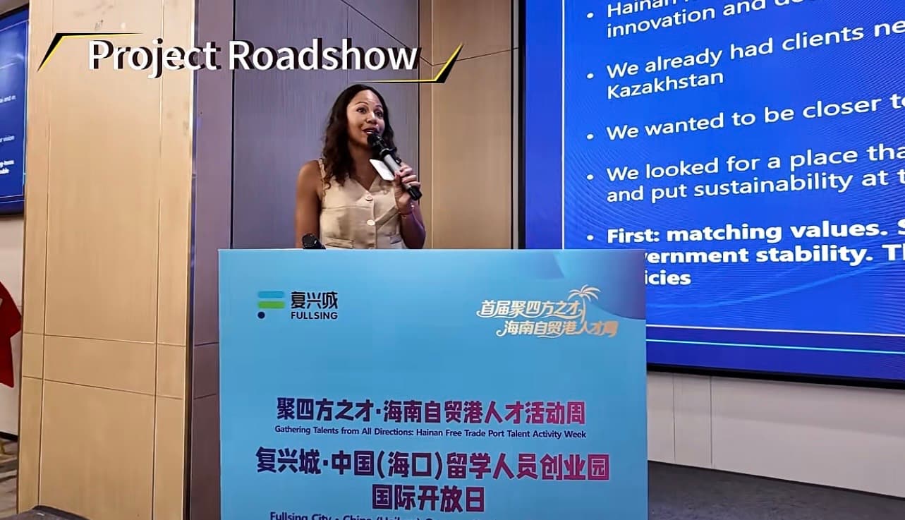 Woman presenting at a podium with a large digital screen during a Project Roadshow event.